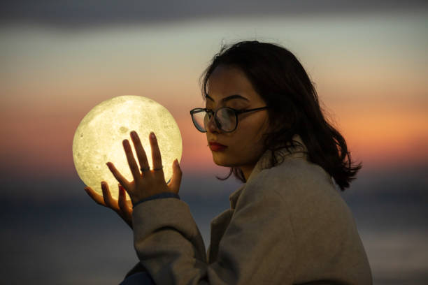 istock Pretty young woman is playing with a moon shaped artificial lamp at sunset. 1787897825