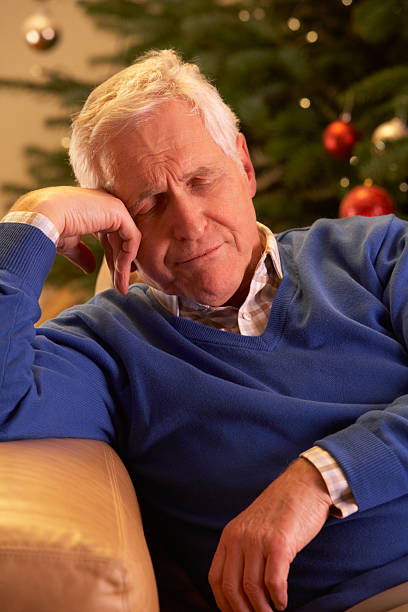 istock Tired Senior Man Relaxing In Front Of Christmas Tree 178790549