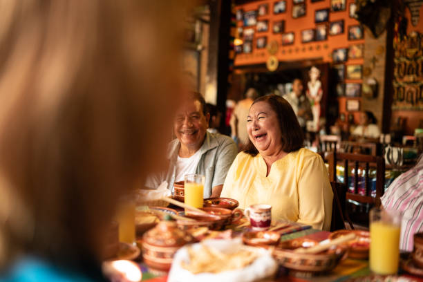 istock Mature woman laughing while talking with her friends at restaurant 1787965690