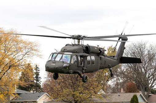 Arlington Heights, IL, USA - November 10, 2023: Blackhawk helicopter at Hersey High School in honor of Veterans Day. Soldier is looking out the door as helicopter takes off.