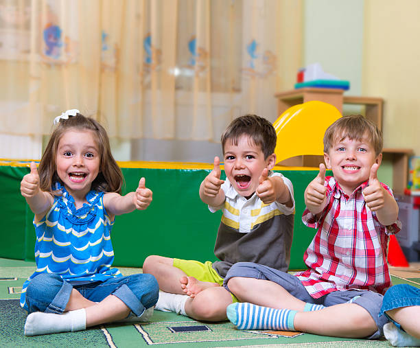 Excited children holding thumbs up stock photo