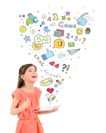 Happy cute little girl in red dress holding a digital tablet in hand and fascinated looking up at the colorful icons of different entertainment apps. Isolated on white background