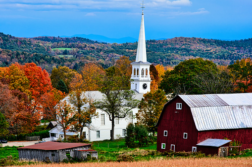 Church and barn surrounded by autumn colors in Peacham, Vermont.