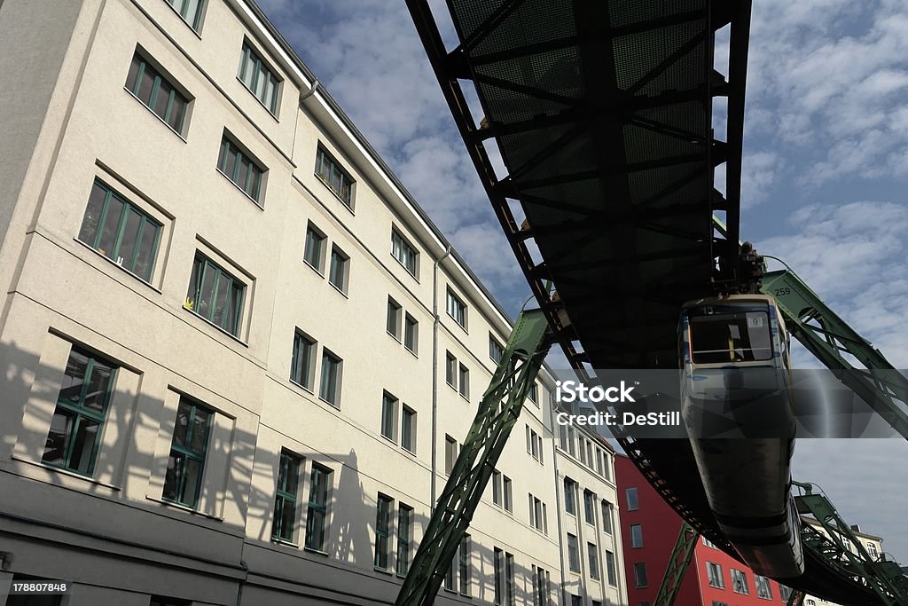 overhead railway in the city seen from below "In Wuppertal, a german city at a river between hills named Wupper, there is an overhead railway between the districts, that is singular in the world. Here you can see it between some houses. The dominating colours are red, green and white under a blue cloudy sky." Aerial View Stock Photo