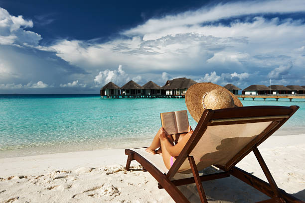 giovane donna leggendo un libro in spiaggia - chair beach chaise longue isolated foto e immagini stock