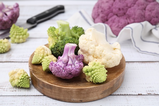 Various cauliflower cabbages on white wooden table