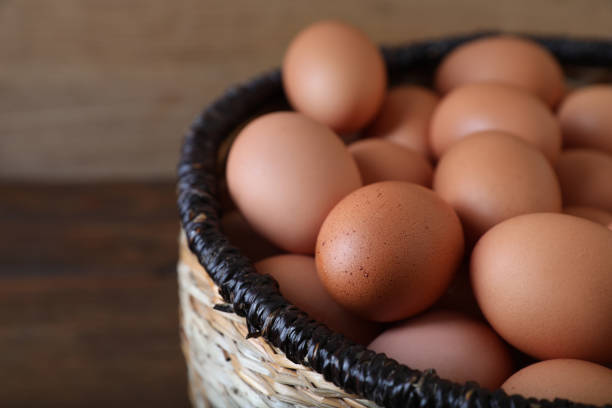 istock Raw chicken eggs in wicker basket on wooden table, closeup. Space for text 1788082066