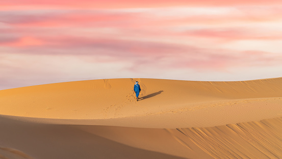 Unidentified Berber man in his traditional clothing, a long robe on sand dunes in Sahara Desert, Morocco