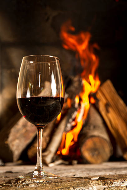 istock Red wine cup glass with fireplace on the background. 178810385