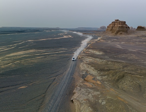 A large truck drives along an unpaved road, surrounded by the natural beauty of an orange-hued rock formation