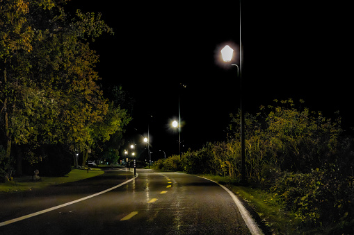 A cycle path at night with some light on and tree surrounding it