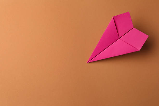 istock Handmade pink paper plane on brown background, top view. Space for text 1788117644