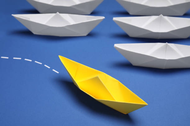 istock Yellow paper boat floating away from others on blue background, closeup. Uniqueness concept 1788120896
