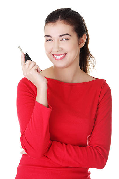 Smiling woman in a red top poses with a car key stock photo