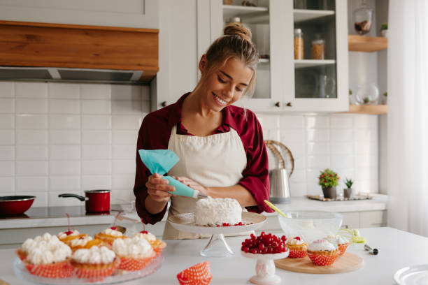 istock Joyful female baker applying whipped cream while decorating cake at the kitchen 1788134193