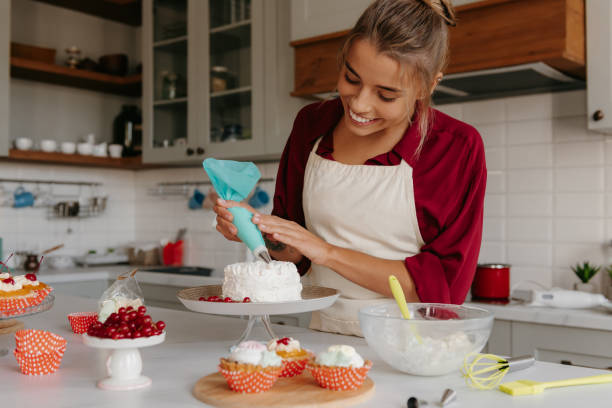istock Confident female pastry chef applying whipped cream while decorating cake at the kitchen 1788134194