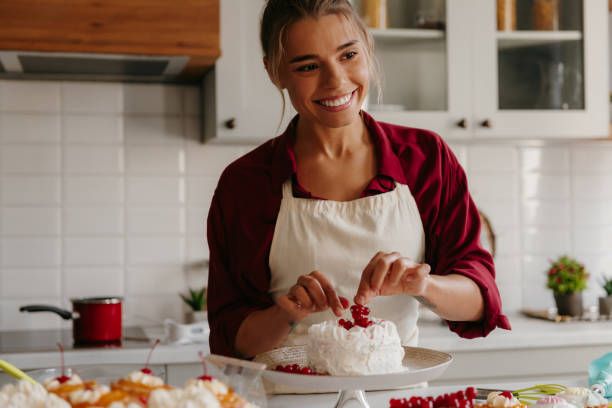 istock Happy female baker decorating cake with berries while standing at the domestic kitchen 1788134211