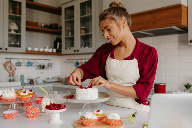 istock Smiling female confectioner decorating cake with berries while standing at the domestic kitchen 1788134757