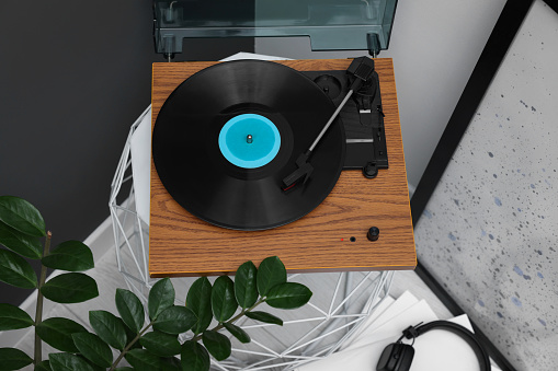 Stylish turntable with vinyl record on coffee table in room, above view