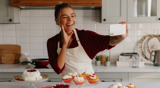 istock Joyful female baker using smart phone while making selfie with various sweet food laying on the table 1788148010