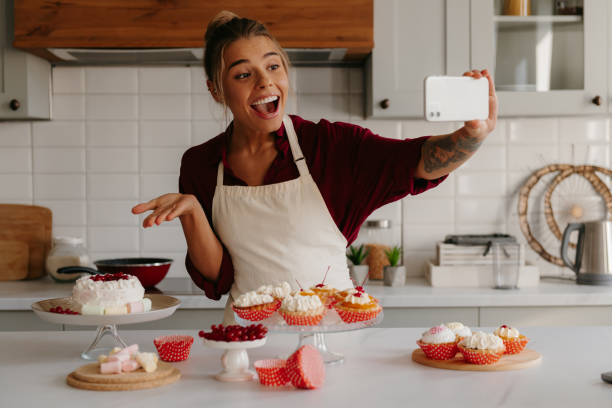istock Happy female baker using smart phone while making selfie with various sweet food laying on the table 1788148011