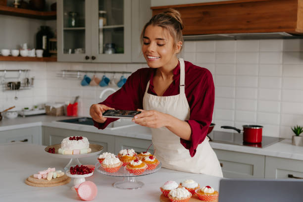 istock Happy female baker using smart phone while photographing various desserts laying on the kitchen table 1788148012