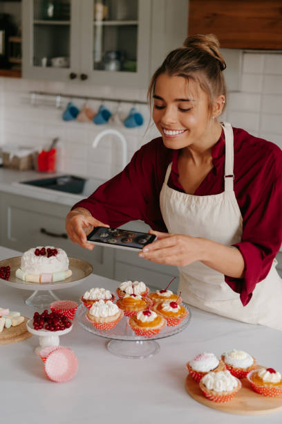 istock Joyful female baker using smart phone while photographing various desserts laying on the kitchen table 1788148013