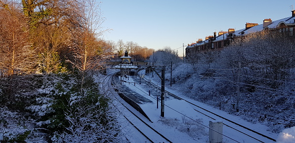 A train station, platform, railway tracks and surrounding area all covered with snow in Glasgow Scotland UK