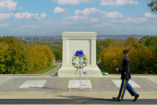 Arlington, United States - May 11, 2013: A single soldier of the ArmyÕs 3rd Infantry Regiment serves as Sentinel at the Tomb in the rain at the Tomb of the Unknowns at Arlington National Cemetery near Washington DC. He is walking the mat past the tomb where a memorial wreath has been placed.