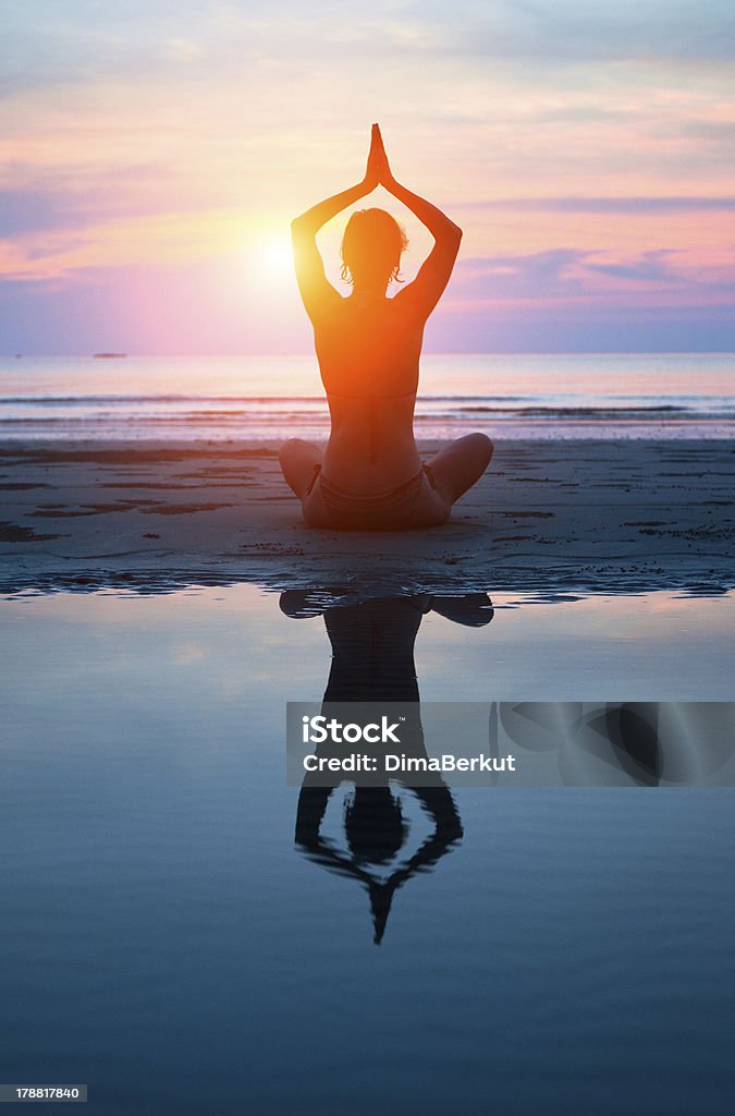 Young woman practicing yoga on the beach at sunset Young woman practicing yoga on the beach at sunset (with reflection in water) Activity Stock Photo