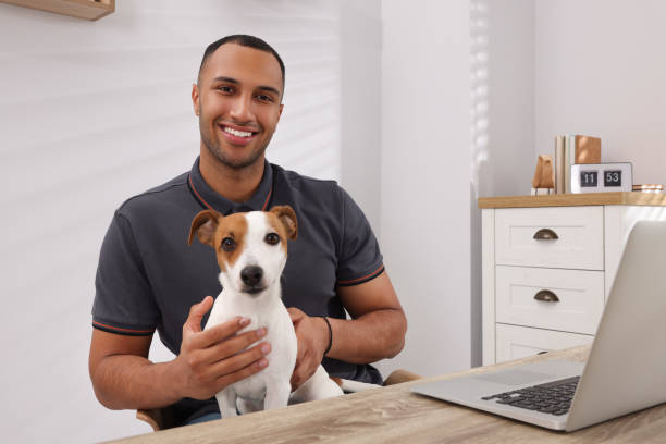 istock Young man with Jack Russell Terrier at desk in home office 1788180496