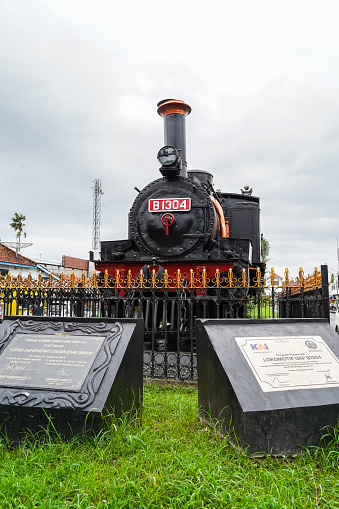Cirebon, Indonesia, February 11 2023: A monument to an old model steam locomotive is displayed in the area in front of the road to the Kejaksan Railway Station