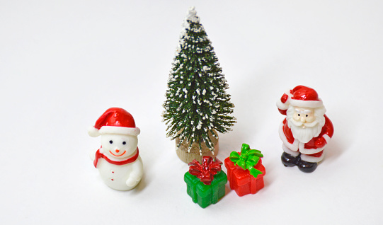 Christmas and New Year background with fir tree, snowman, gifts and santa claus. greeting card. small toy miniatures for home or office decoration for the Christmas holidays