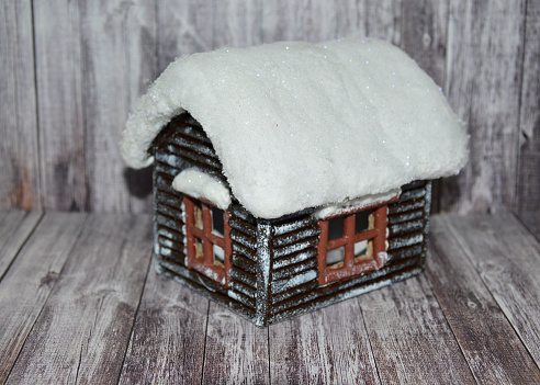 small decorative house with windows and snow on the roof on a wooden background. decorating a room and office for the Christmas holidays. concept of buying a home, mortgage and rental property