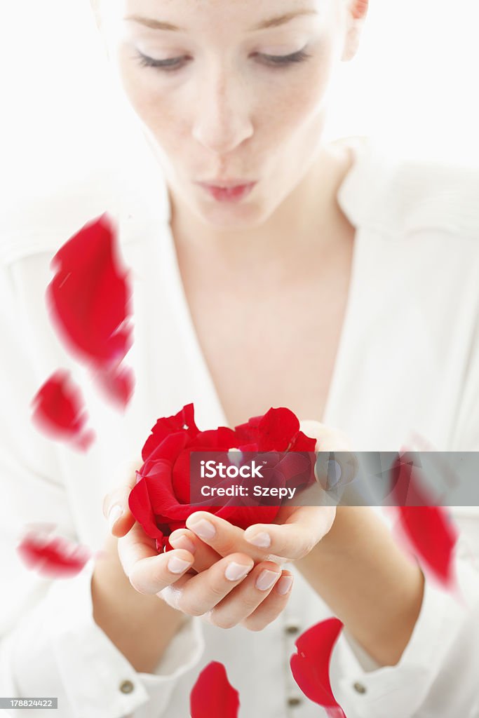 Hermosa joven mujer Soplando rojo pétalos de rosa desde su palms - Foto de stock de Adulto libre de derechos