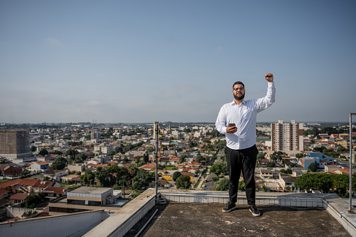 Portrait of latin man holding cell phone with raised fist