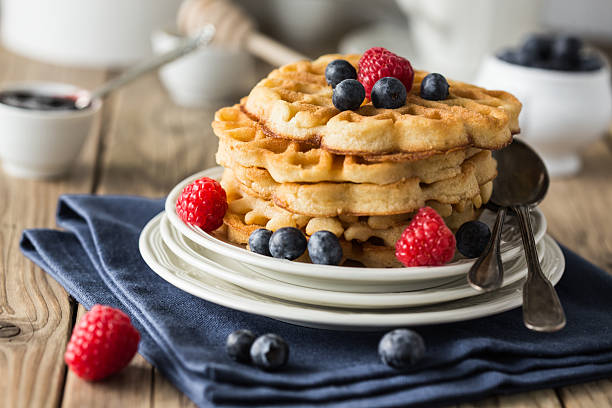 Waffles adorned with blueberries and strawberries on a plate Blueberry waffles with raspberries for breakfast waffle stock pictures, royalty-free photos & images