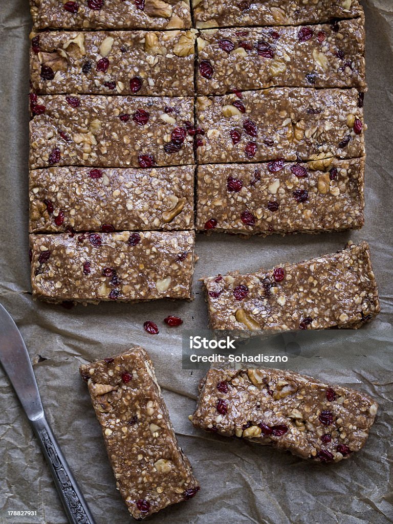 Homemade chewy granola bars, view from above Homemade chewy granola protein bars made of peanut butter, honey, nuts and cranberries with cacao on a baking paper background, cut into servings. View from above.   Protein Bar Stock Photo
