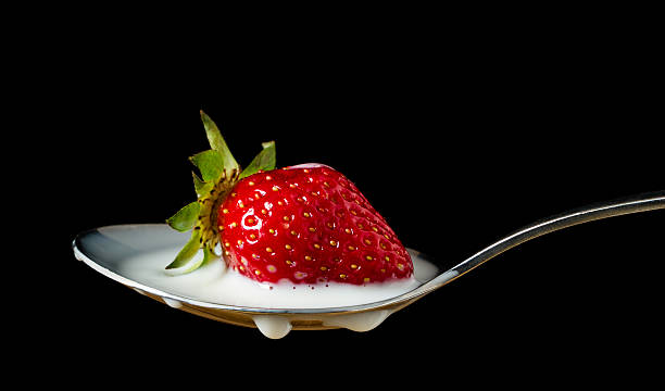 istock red, ripe strawberry falling in spoon with milk 178828540