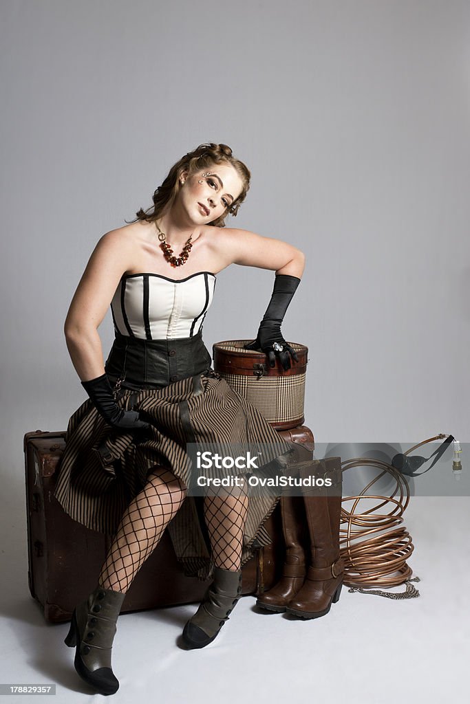 Gorgeous Brunette Steampunk Woman An attractive, brunette woman sits in a steampunk setting on a trunk. 20-29 Years Stock Photo