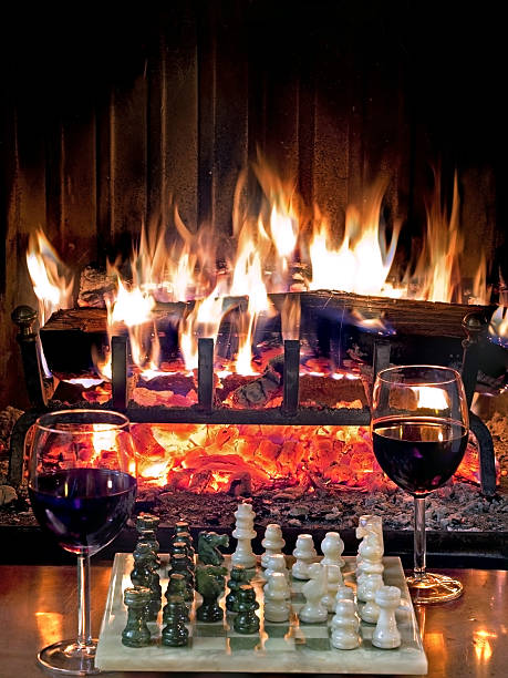 play chess drinking red wine in front of a roaring stock photo