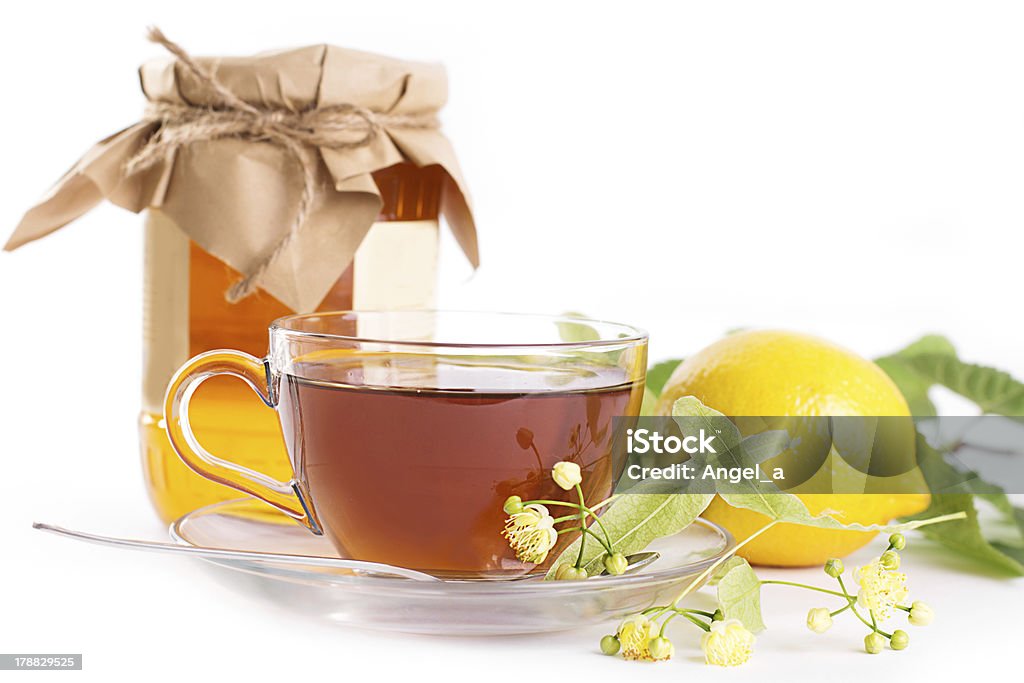 Lemon tea with linden honey jar and flowers Lemon tea with linden honey jar and flowers over white Branch - Plant Part Stock Photo