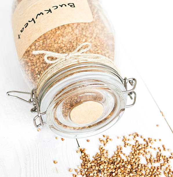 istock Overturned  glass jar with grains  on a white wooden background 178829536