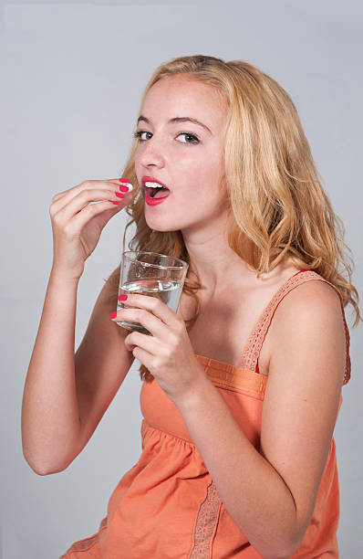 Teenage girl taking a pill stock photo