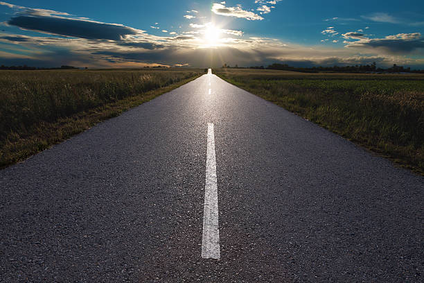 istock Driving on an empty road towards the setting sun 178830472
