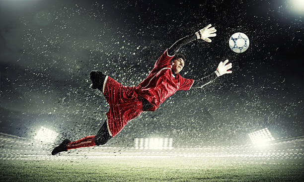 Goalkeeper catches the ball in soccer game stock photo