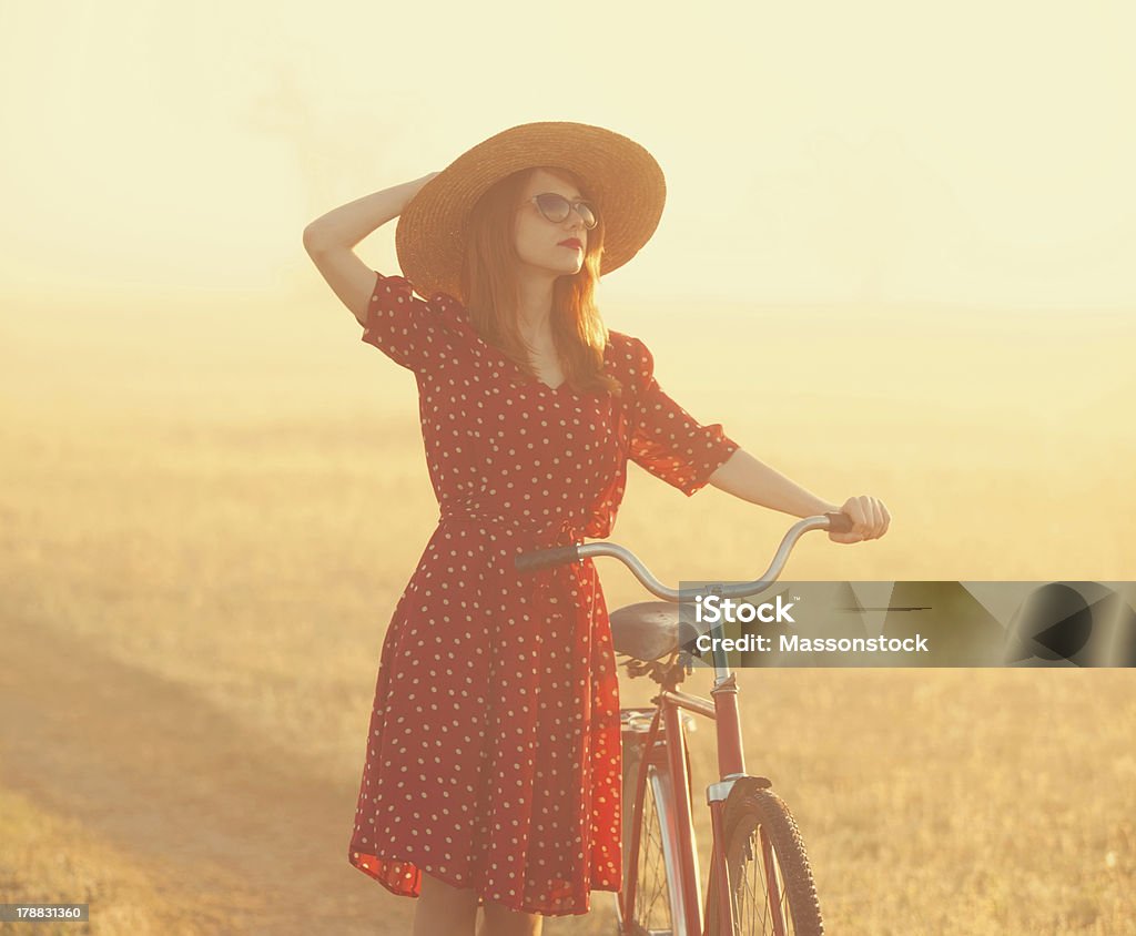 Girl on a bike in the countryside Girl on a bike in the countryside in sunrise time. Adult Stock Photo