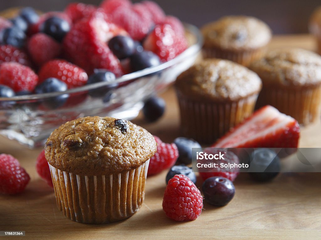 Fresh Berry Muffins Blueberry Muffins with fresh raspberries, strawberries, blueberries on a wooden cutting board. Berry Fruit Stock Photo