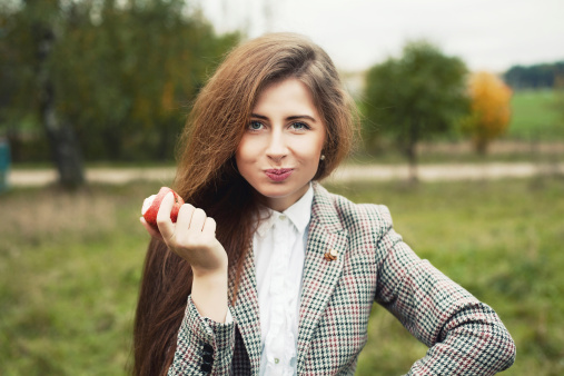 Woman eating apple outdoors in autumn