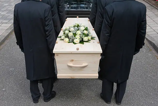 Bearers a carrying a coffin into a car